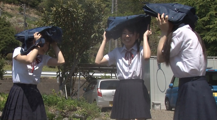 下校中に雨が降り出したのでスクールバッグで濡れるのを防ぐ女子校生たち